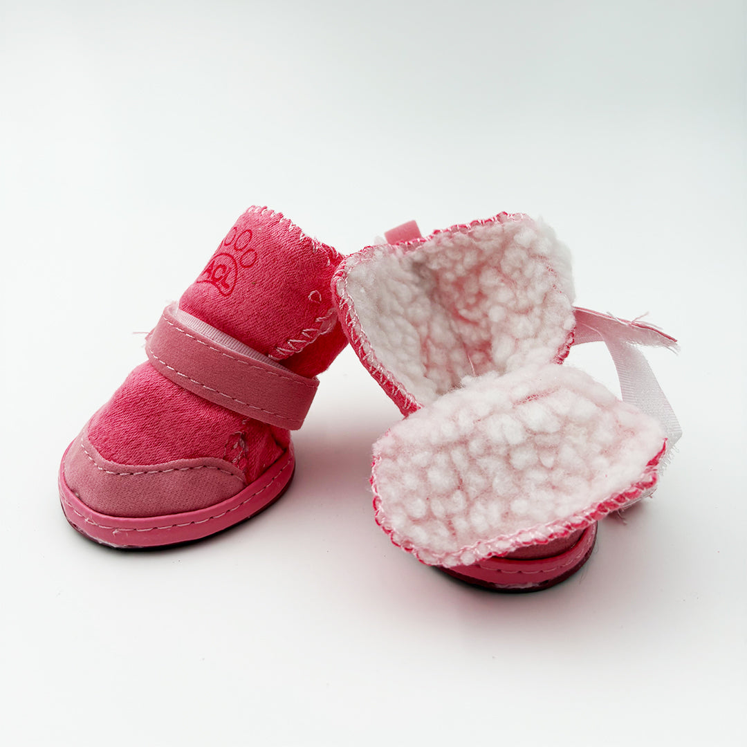 Pair of pink dog boots with white fur lining on a light background